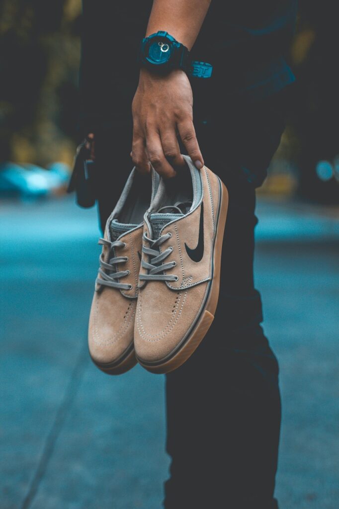 A boy is standing with stylish shoes in his hand which are of light brown colour